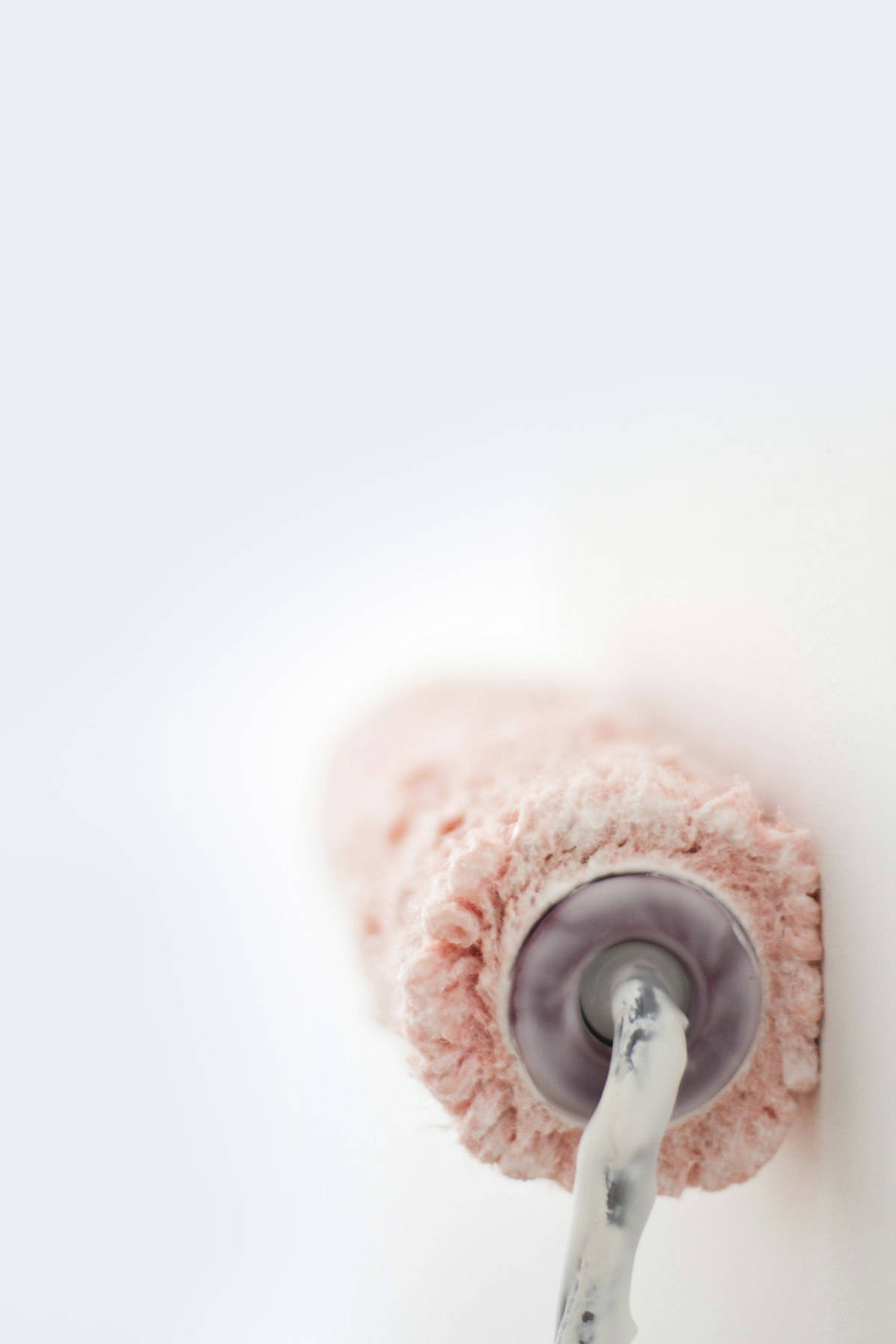 Rosa Wischmopp an weißer Wand